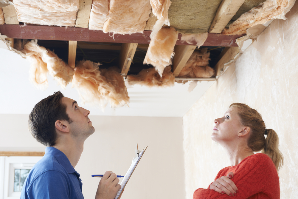 A home inspector and home buyer looking at a roof with concerned look